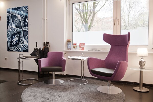 A modern room with two purple chairs, a small table, a rug, and a large abstract painting on the wall.
