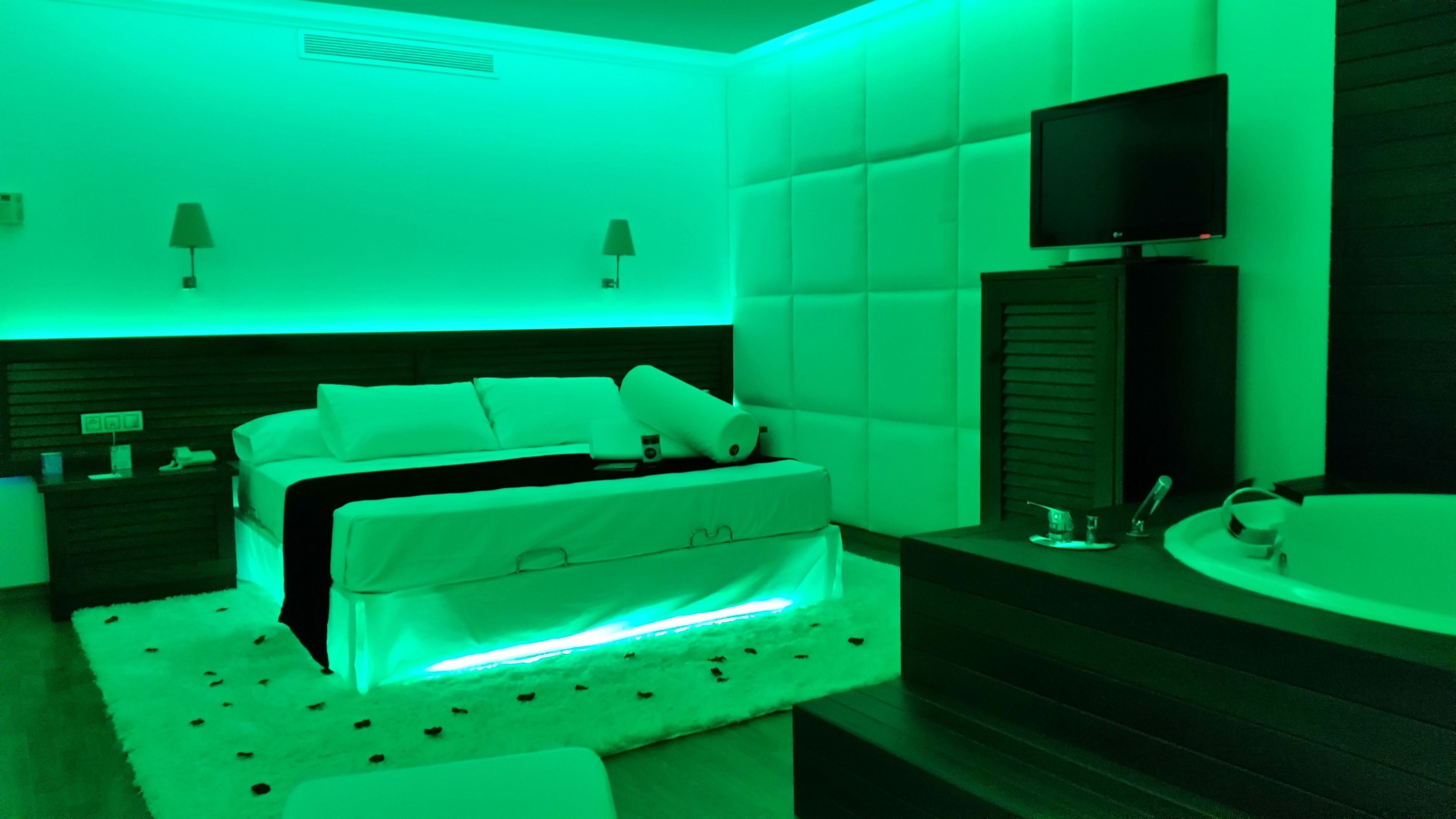 Un dormitorio moderno con cama, mesitas de noche, televisor y baño con bañera.