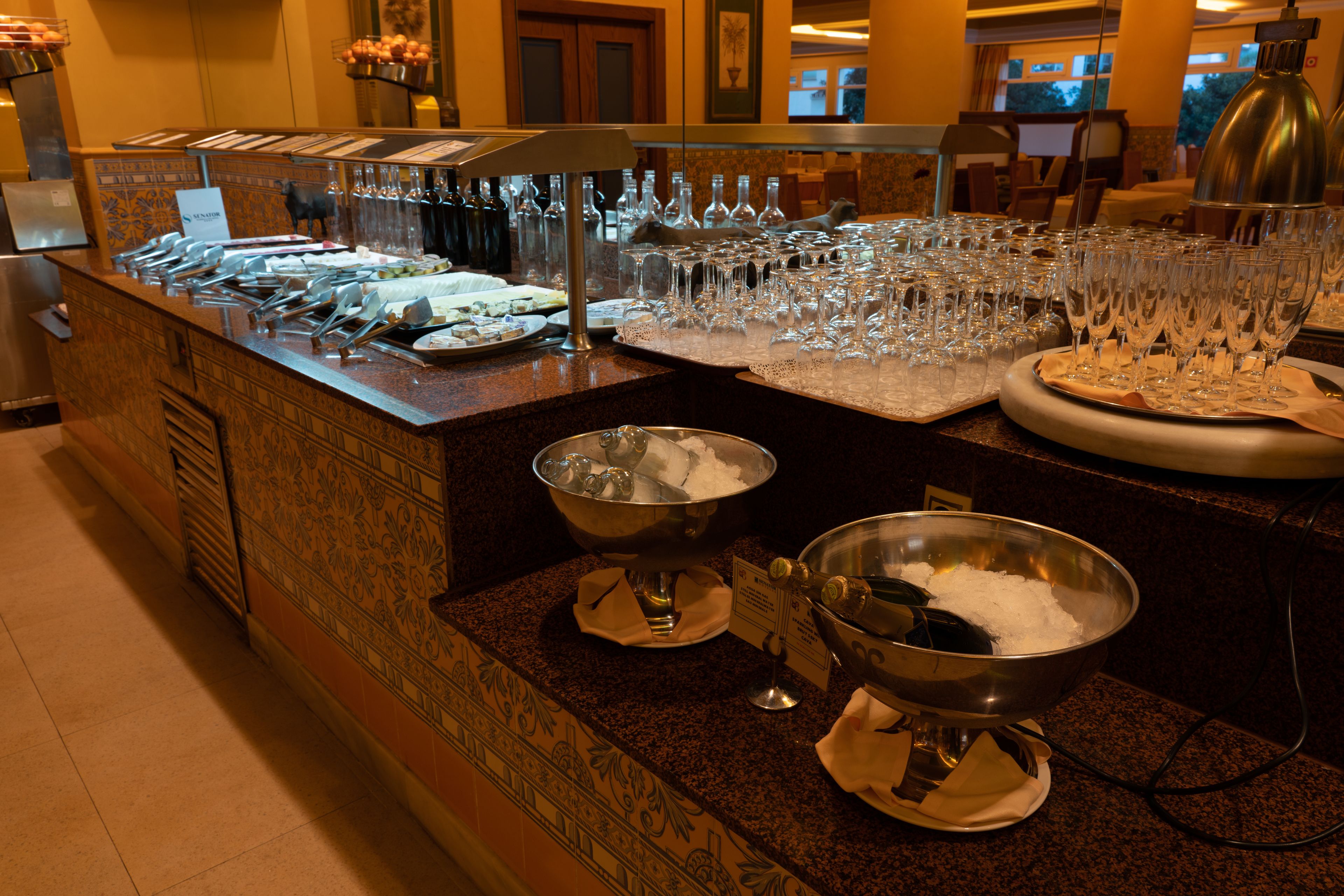 Una mesa de buffet con diversos platos y una gran cantidad de copas de vino.