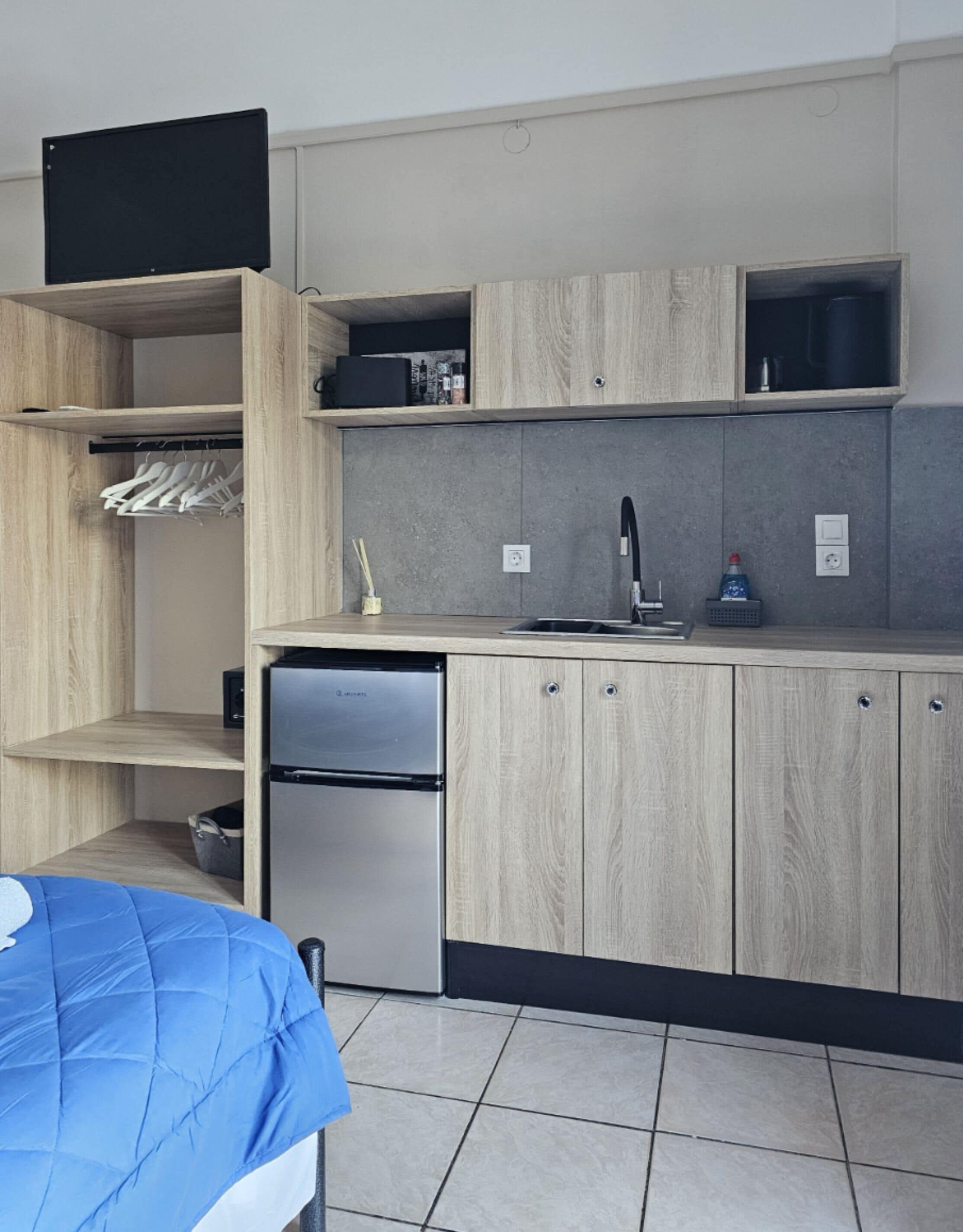Una cucina compatta con frigorifero integrato, lavello e mobili in legno.