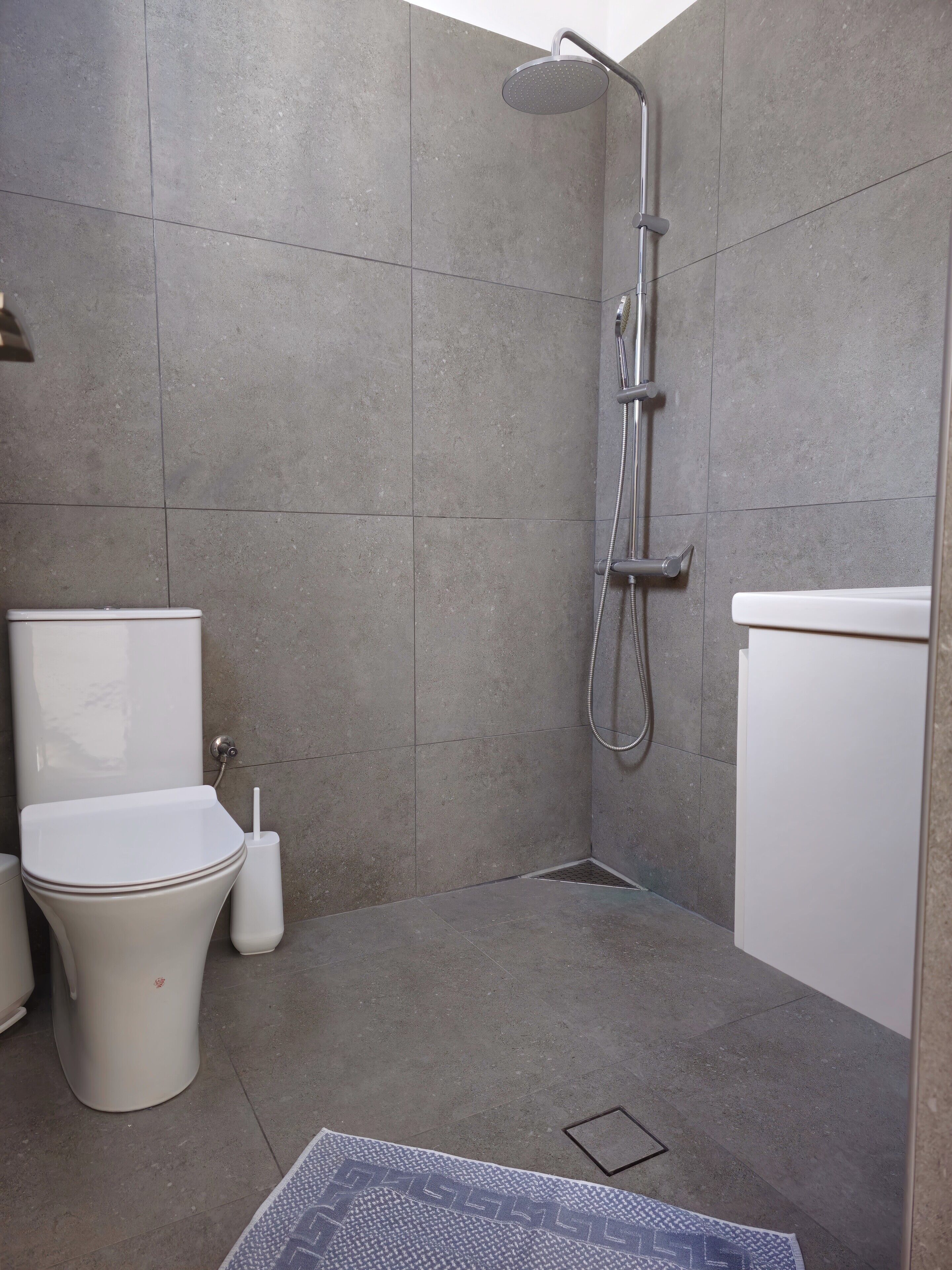A bathroom with a shower, toilet, and bidet.