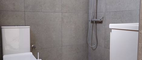 A bathroom with a shower, toilet, and bidet.