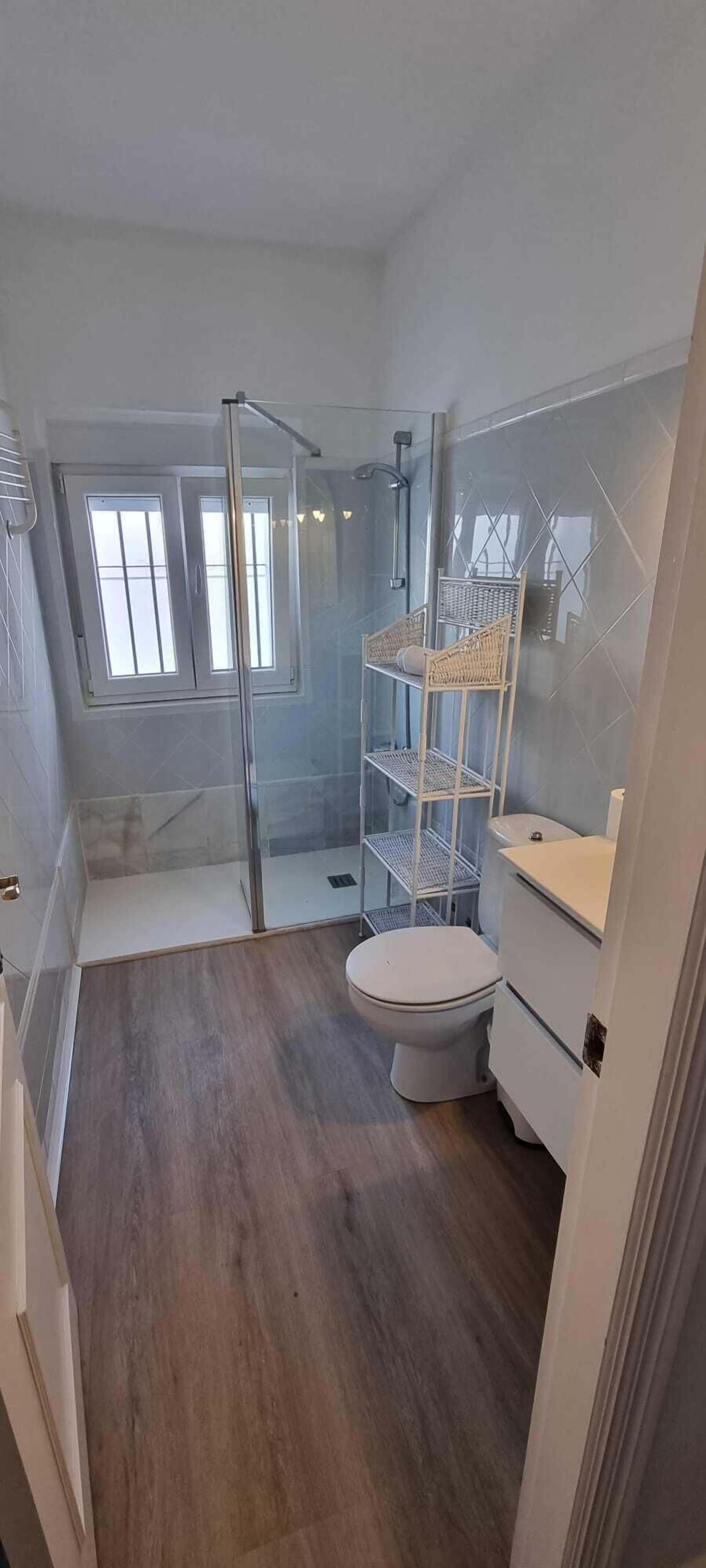 Un baño con cabina de ducha de vidrio, inodoro y lavamanos blanco.