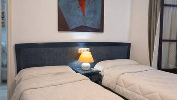 A hotel room with two beds, a nightstand with a lamp, and a painting on the wall.