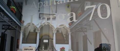 A hotel interior with a staircase, a sign reading "EMPUJAR", and a large window displaying "Apartamentos La 70".