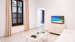 Una sala de estar moderna con una televisión, una mesa de centro de vidrio y un sofá blanco.