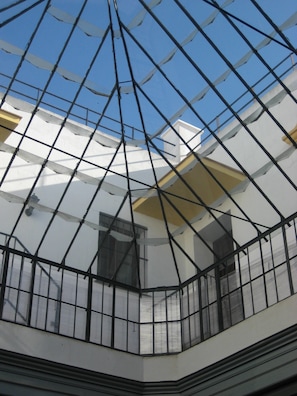 Ein Atrium mit Glasverkleidung und einem geometrischen Deckenmuster, das natürliches Licht hereinlässt.