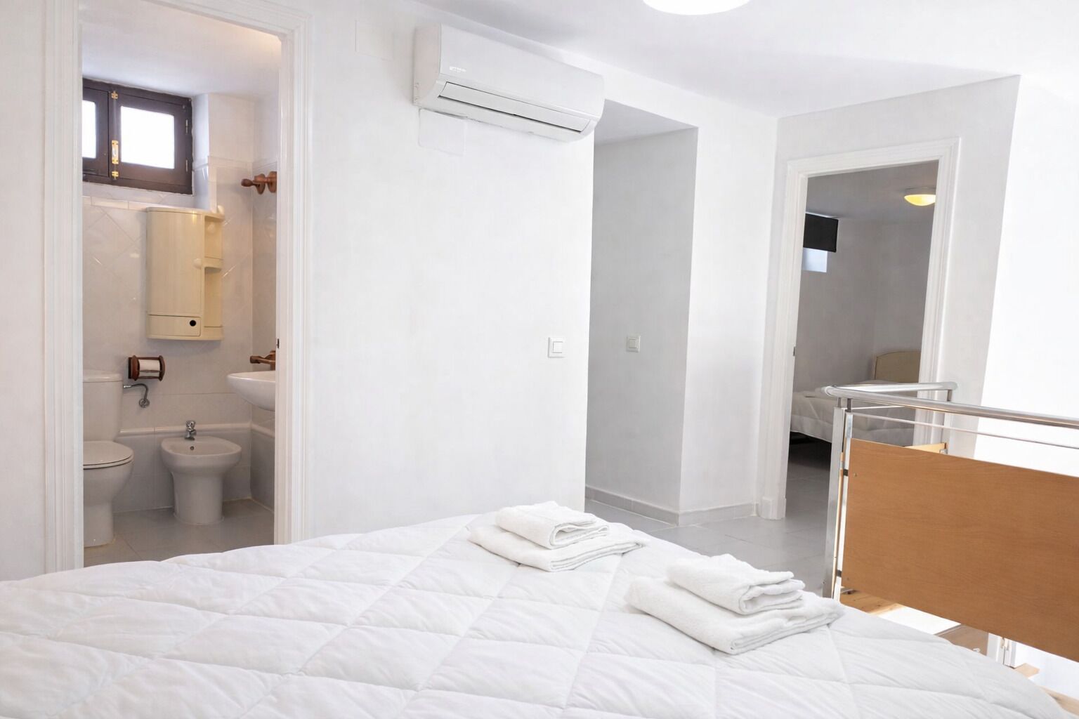 Een hotelkamer met een bed, een badkamer en uitzicht op een andere kamer.