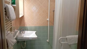 Un baño con ducha, inodoro, lavamanos y toallero.