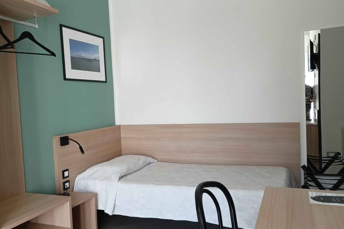 A compact room with a bed, a desk, and a wardrobe.
