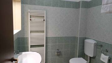 A bathroom with a toilet, sink, towel rack, and a white towel hanging on the wall.