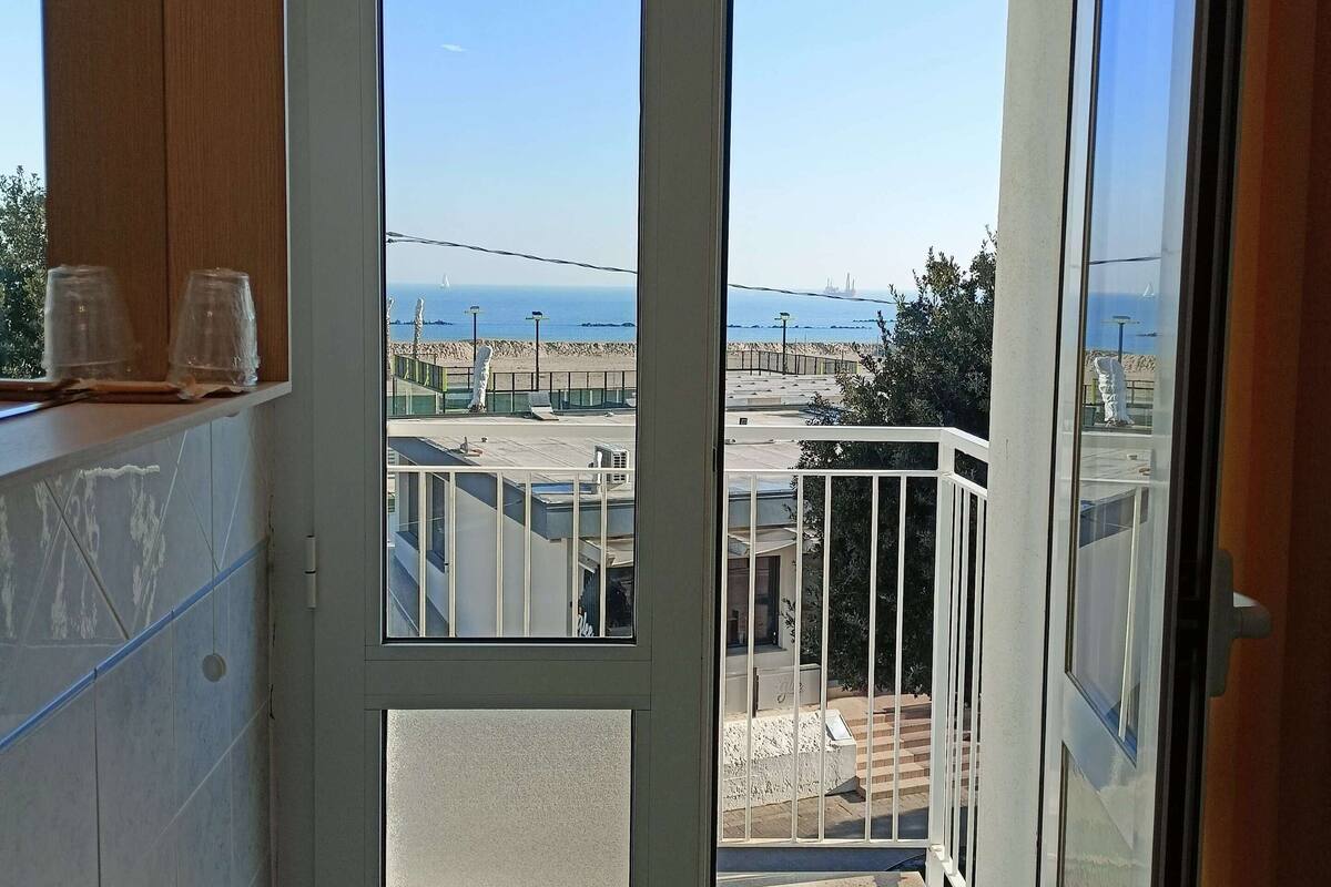 A bathroom with a large window and a view of the sea.