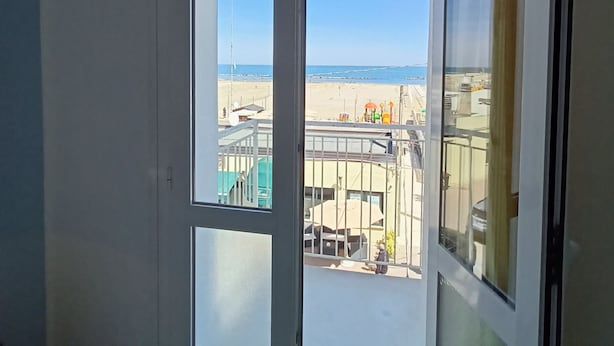 Een kamer met een grote schuifglazen deur die uitkomt op een balkon.