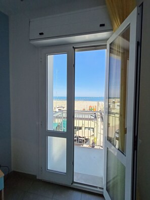 Una habitación con un amplio ventanal corredera que da a un balcón exterior.