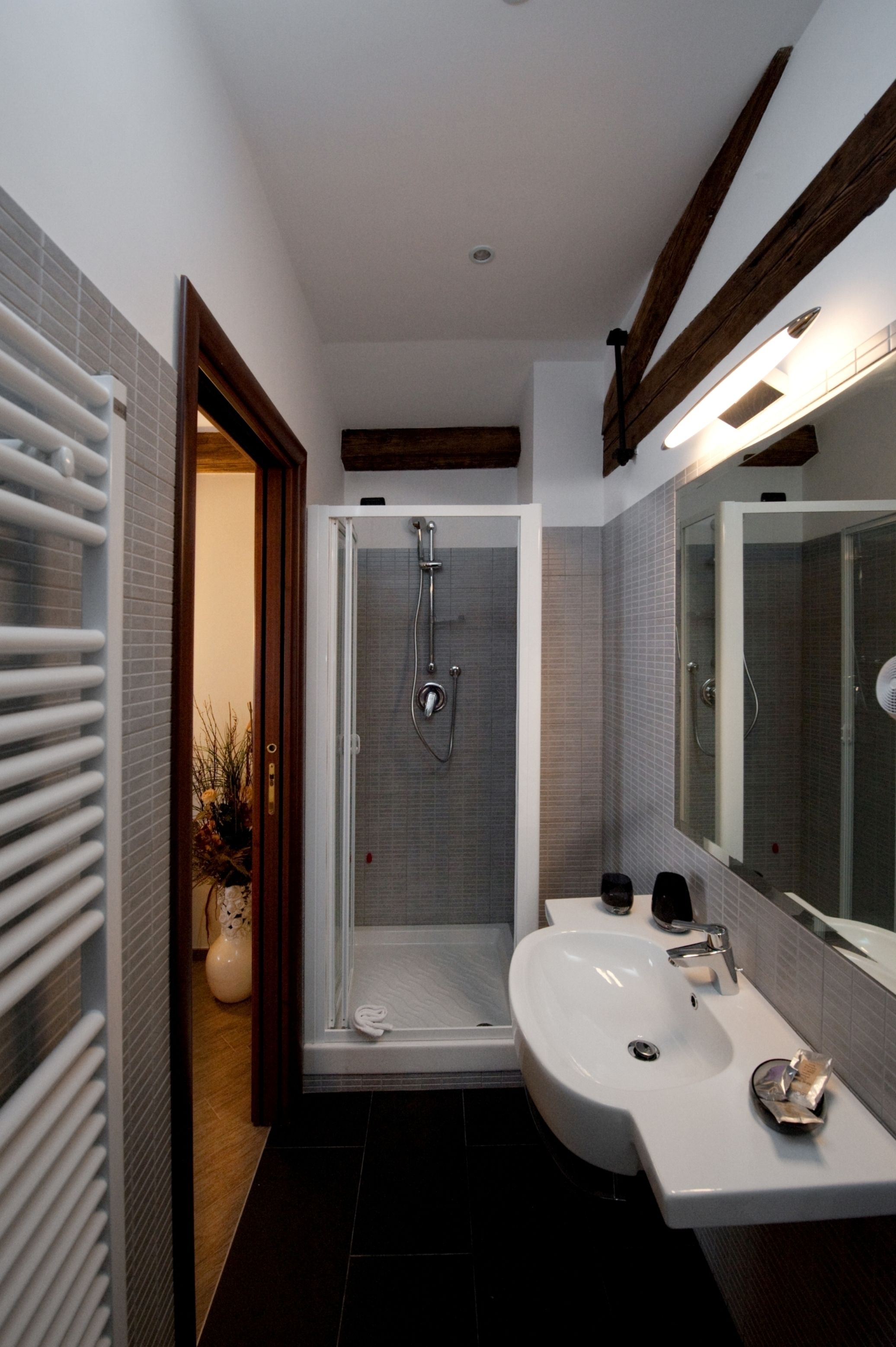 A modern bathroom with a glass-enclosed shower, a white sink, and a large mirror.