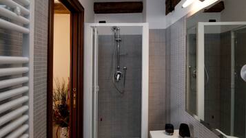 A modern bathroom with a glass-enclosed shower, a white sink, and a large mirror.