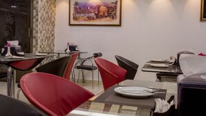 Un restaurant doté d’un plafond au design moderne, de carreaux muraux à motifs et de chaises rouges.
