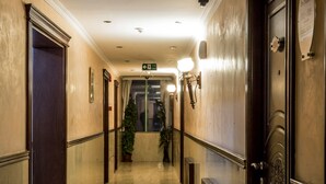 Un couloir d’hôtel avec un sol ciré, une horloge et un panneau indiquant la sortie.