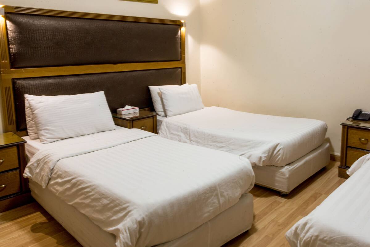 A hotel room with two single beds, a wooden headboard, bedside tables with lamps, and a bedside telephone.