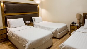 Habitación de hotel con dos camas individuales, cabecero de madera, mesitas de noche con lámparas y teléfono junto a la cama.