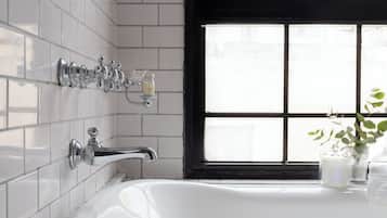 Un baño con una bañera blanca, una ventana de marco negro y una toalla en el suelo.