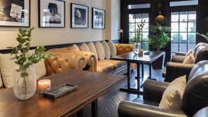 Un salon moderne avec un canapé en cuir, une table basse en bois et des œuvres d’art encadrées accrochées au mur.