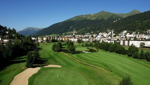 A golf course with a flagstick, sand bunkers, and a pond.