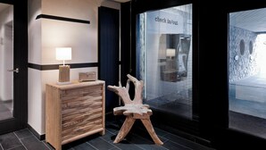 A reception area with a wooden desk, a modern lamp, and a unique wooden chair.