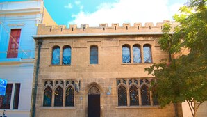 A historic building with a prominent entrance, arched windows, and a stone facade. - Landay Hostel (Santiago)