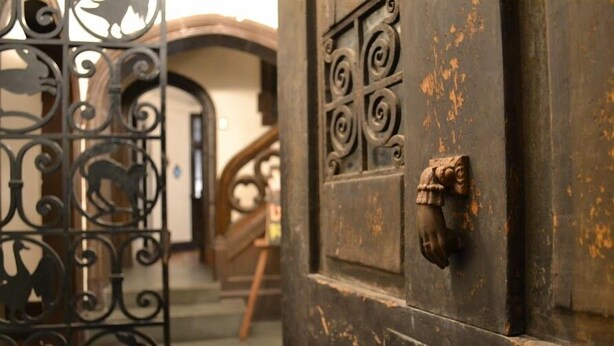 A rustic wooden door with intricate metalwork and a brass handle. - Landay Hostel (Santiago)