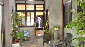 A cozy patio area with a round glass table and metal chairs, surrounded by potted plants and a striped cushion. - Landay Hostel (Santiago)