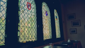 A room with large stained glass windows, a table, and chairs. - Landay Hostel (Santiago)
