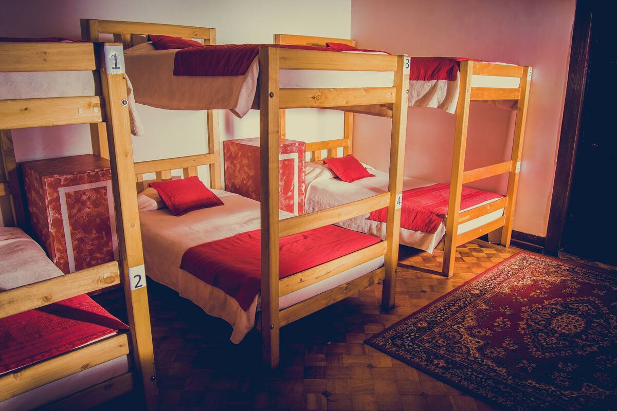 Dormitorio con literas de madera, tres en total, cada una con una etiqueta numérica.