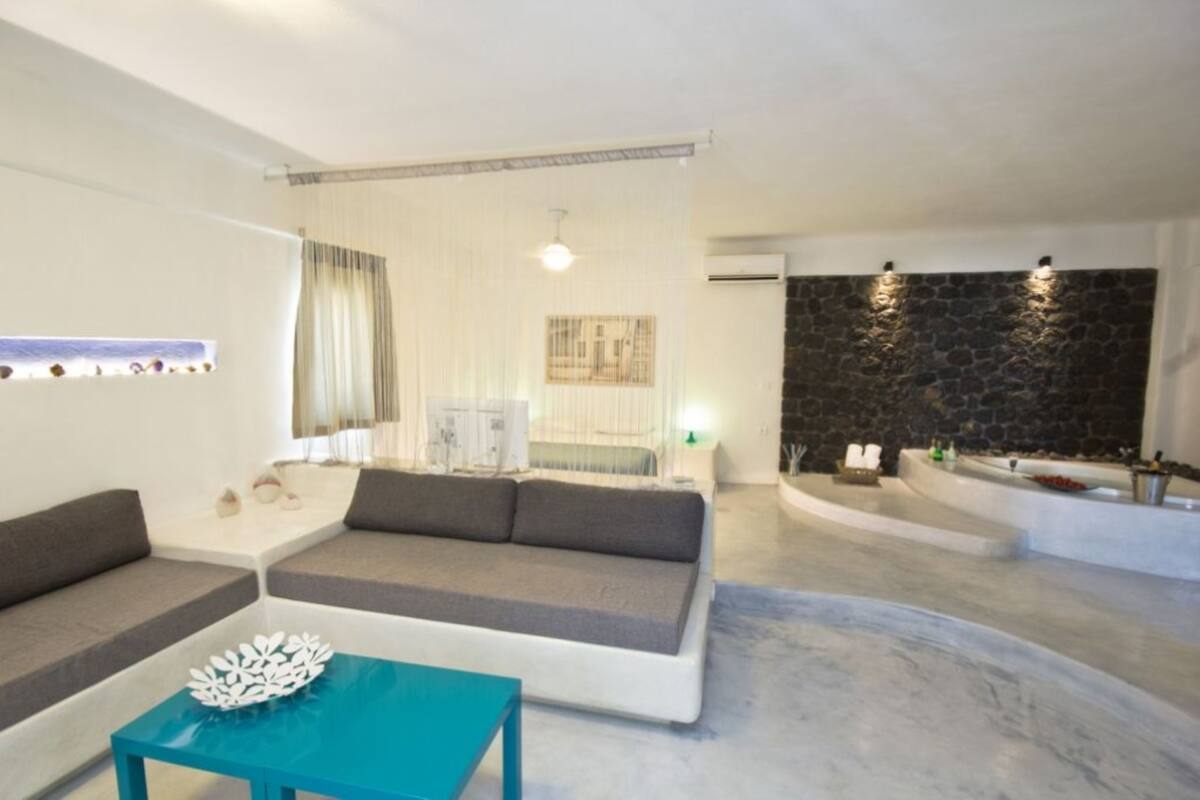 Ein modernes Wohnzimmer mit einer Couch, einem Couchtisch, einer Steinwand und einer Badewanne.