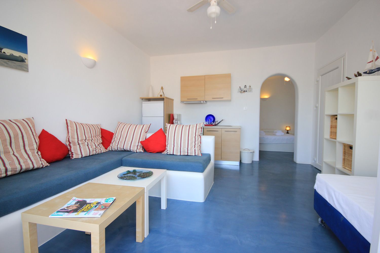 A modern, compact living space with a sofa, coffee table, and a small kitchen area.