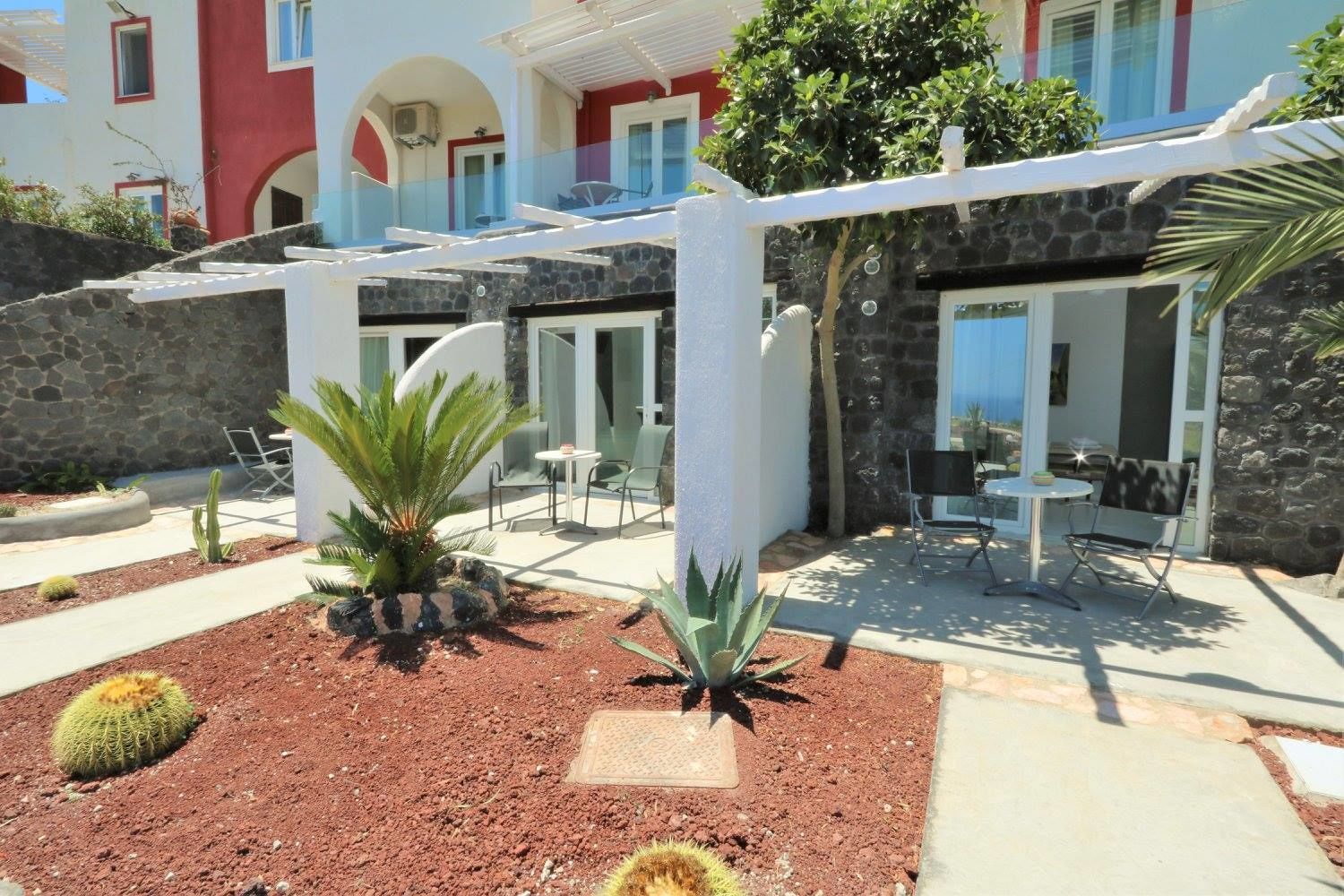 Un patio con mobiliario exterior, un muro de piedra y un jardín de cactus.