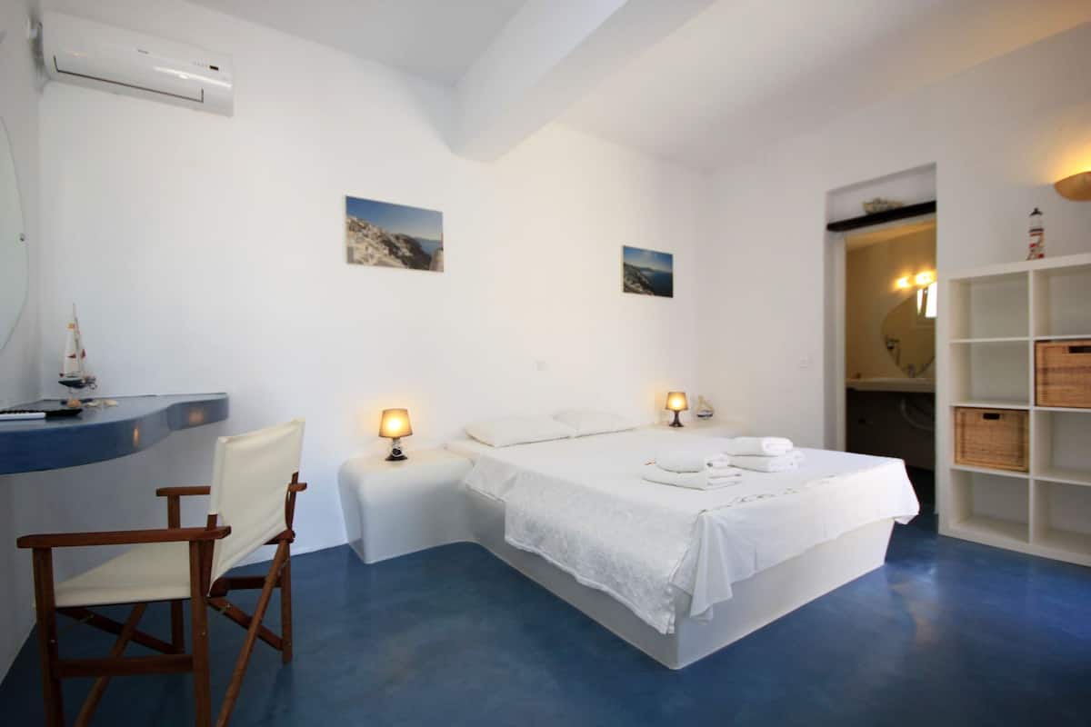 Ein Schlafzimmer mit einem Bett, Nachttischen, einem Schreibtisch, einem Stuhl und einem Regal mit Körben.