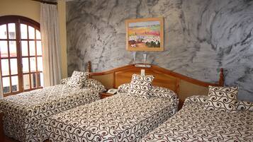 A hotel room with two beds, a wooden headboard, a painting on the wall, and a window with curtains.