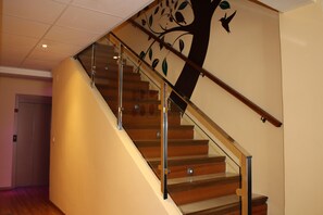 A wooden staircase with glass railings and a tree mural on the wall. - Hotel La Curva (Albolote)