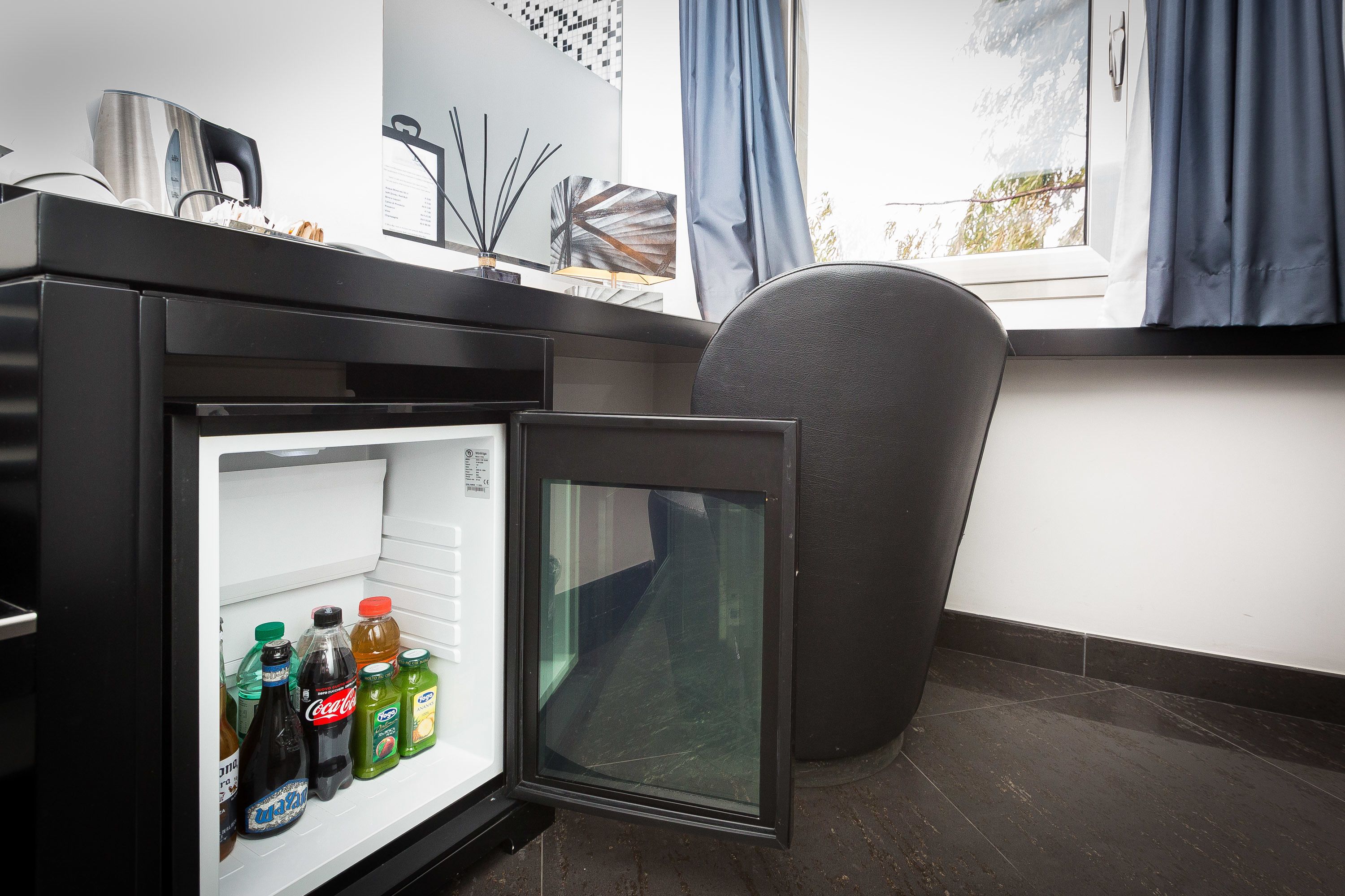 A compact refrigerator with beverages inside, a coffee maker, and a decorative item on top.