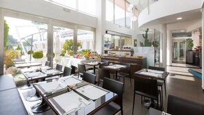 A modern restaurant with high ceilings, large windows, and a variety of seating arrangements. - JC Hotel (Rome)