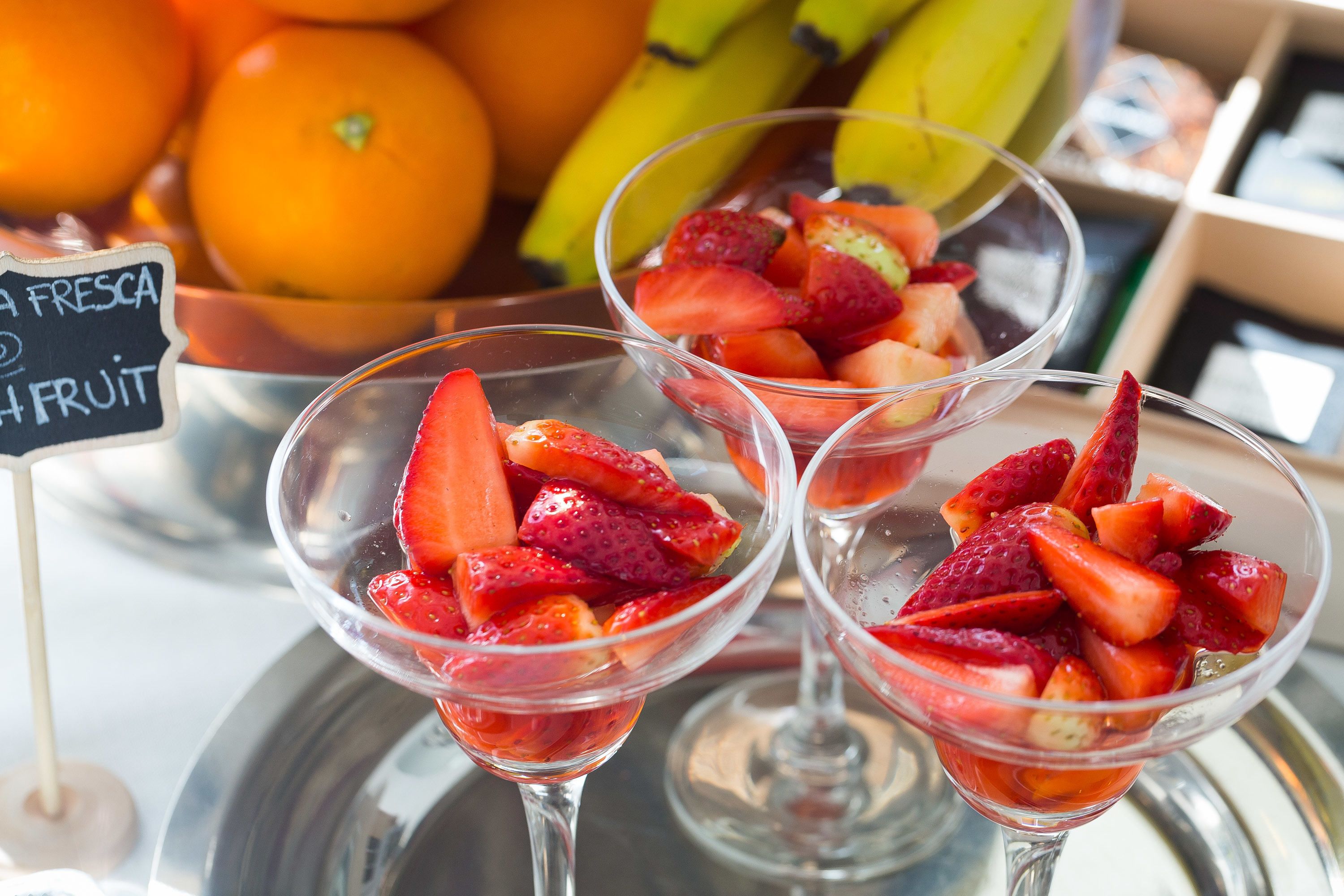 Three glasses of fruit salad with a sign indicating fresh fruit.