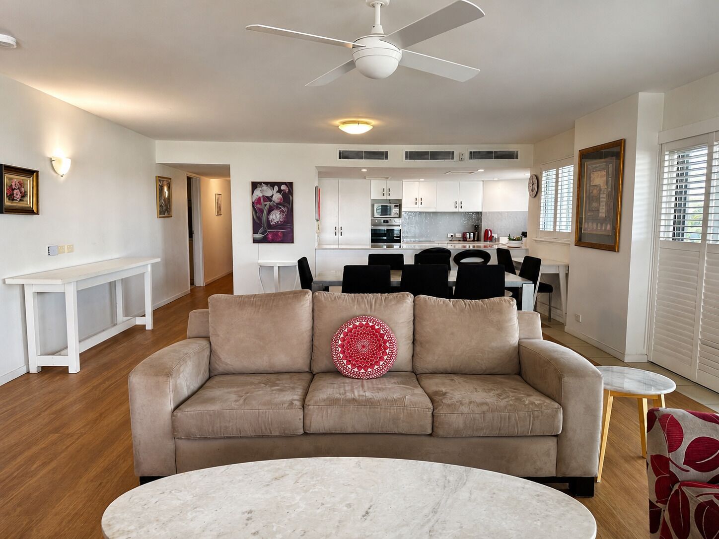 A living room with a beige sofa, a round coffee table, and a ceiling fan.