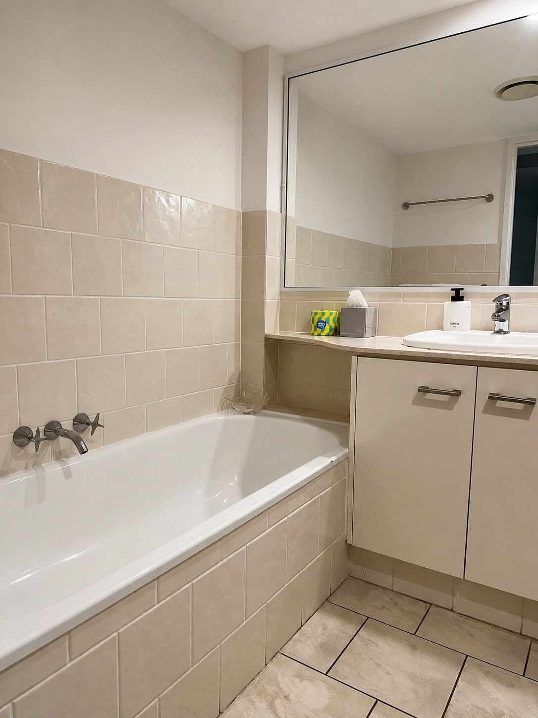 Ein Badezimmer mit einer Badewanne, einem Waschbecken, einem Spiegel und einem Handtuchhalter.