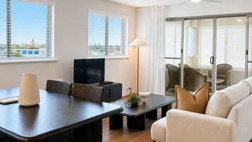 A modern living room with a dining area, large windows, and a view of the cityscape.