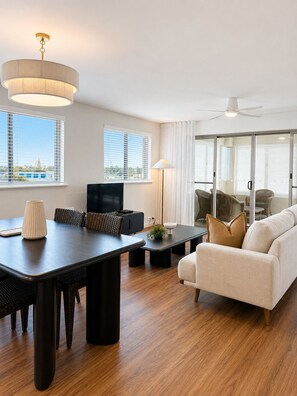Una sala de estar moderna con comedor, ventanas amplias y vistas a la ciudad.