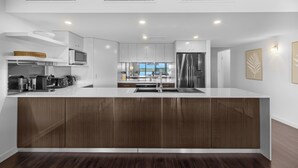 A modern kitchen with a central island, built-in appliances, and a view to the outside. - Riverside Apartments & Hotel Ballina (Ballina)