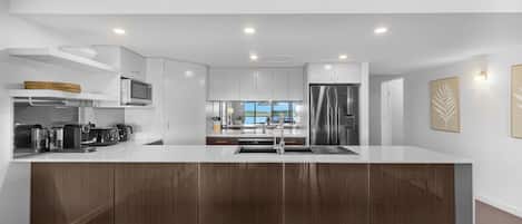 A modern kitchen with a central island, built-in appliances, and a view to the outside.