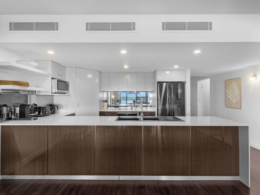 A modern kitchen with a central island, built-in appliances, and a view to the outside.