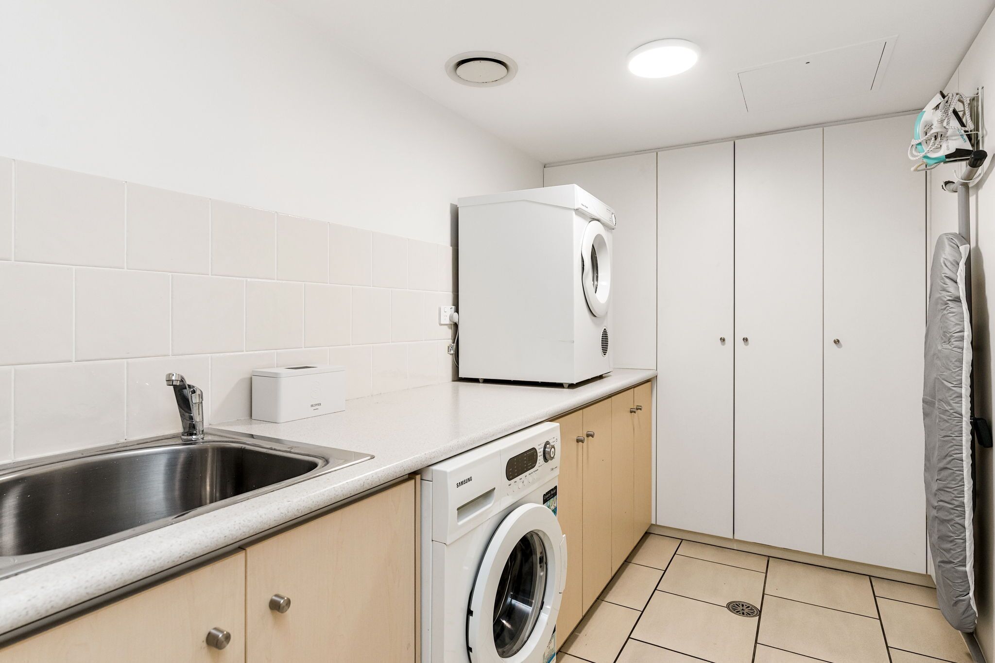 A compact kitchen with a stainless steel sink, a built-in washing machine, and a microwave.